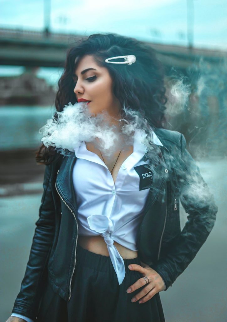 vaping and travelling woman in black leather jacket